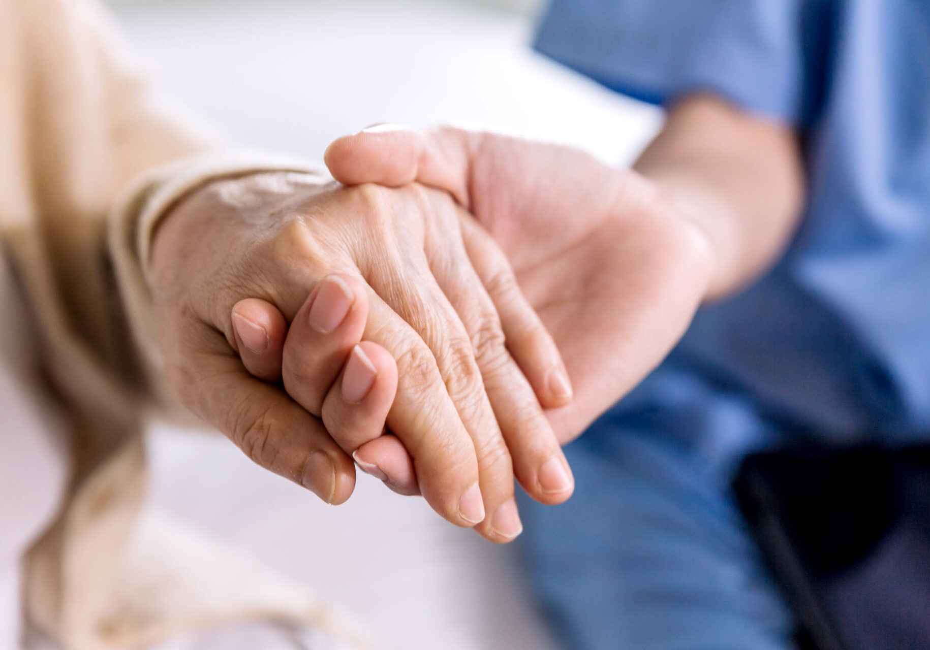 Close-up senior Asian woman hand with her caregiver helping hands holding together, Caregiver visit at home. Home health care and nursing home concept.