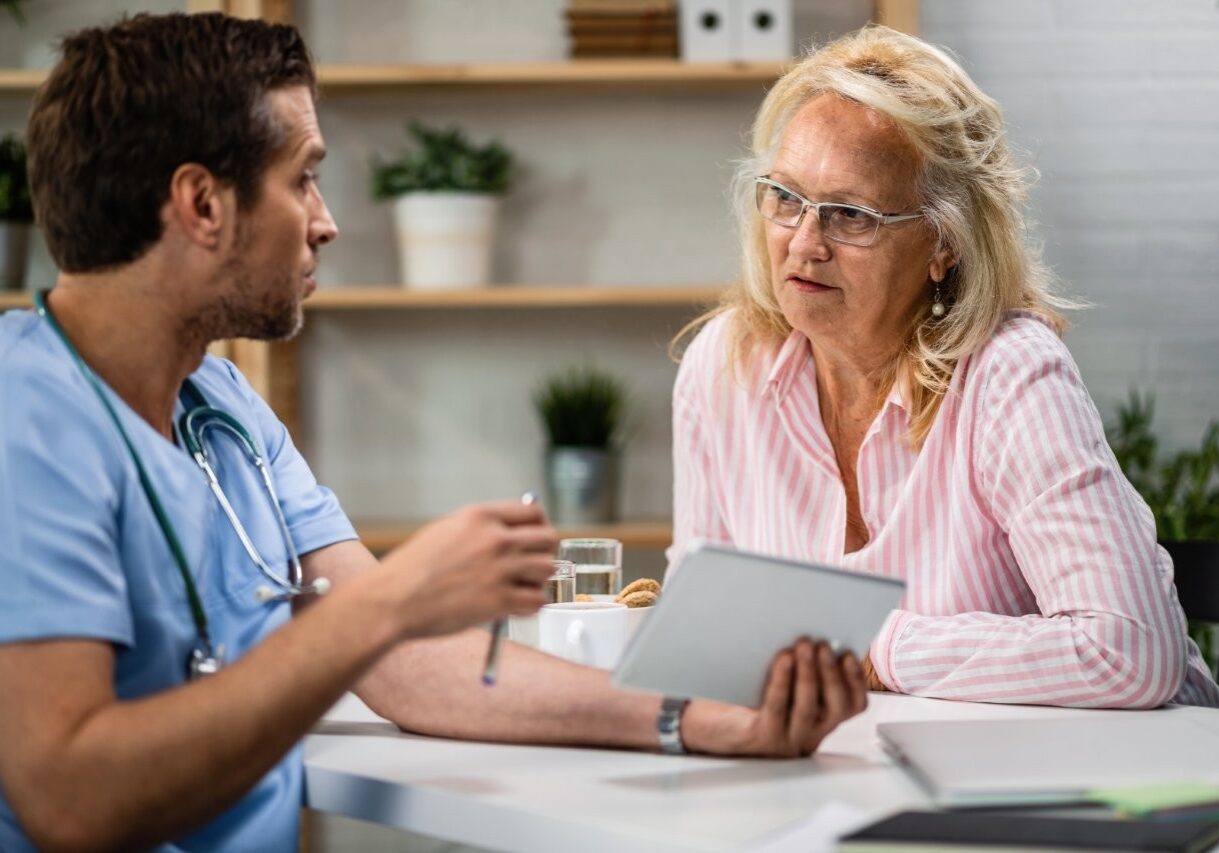 senior-woman-communicating-with-doctor-who-is-using-digital-tablet-explaining-her-medical-test-result